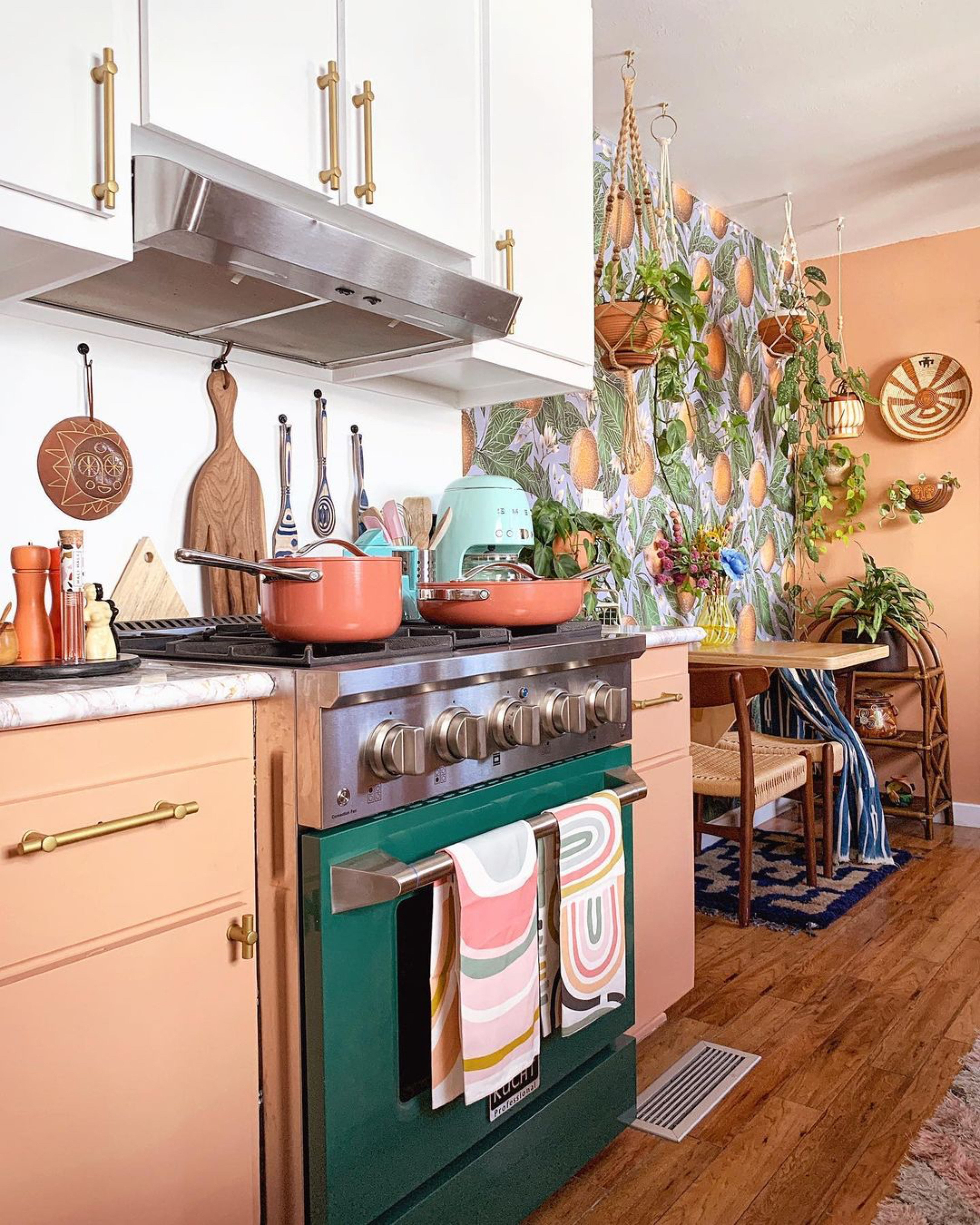 Green stove with peach cabinets and fruity kitchen wallpaper