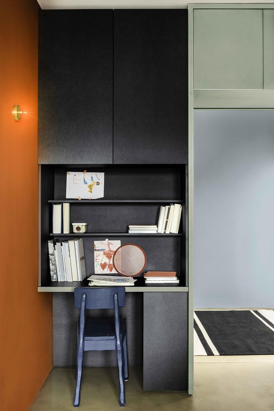 a built in home office against a desk wall, with a blue chair, in a nook in a wider living space