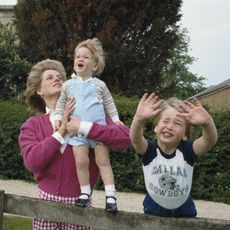 Princes William and Harry with their mother, Diana, Princess of Wales (1961 - 1997) in the garden of Highgrove House in Gloucestershire, 18th July 1986. William is wearing a Dallas Cowboys t-shirt.