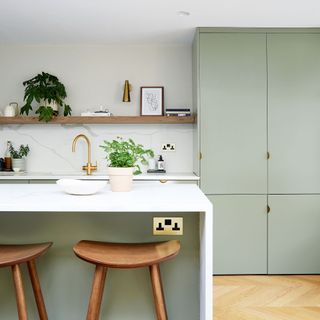 kitchen with wooden flooring white walls and rectangle wash basin with faucet with white marble countertop and wooden chairs