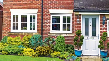 Red brick house with a front gate and a hedge