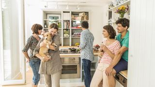 Friends in kitchen, lady carrying dog