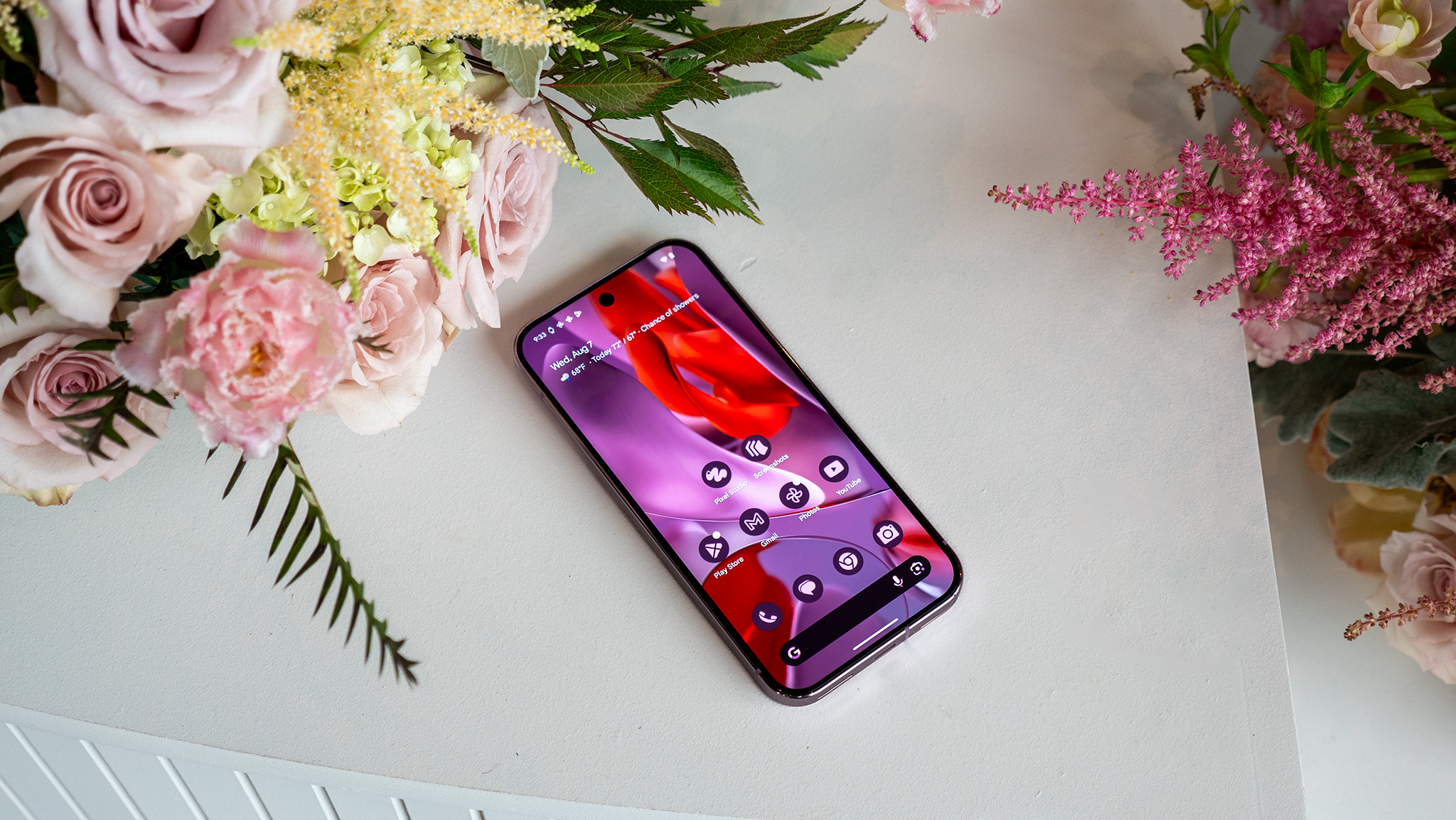 The bright vibrant display of the Google Pixel 9 Pro XL next to a bouquet of flowers