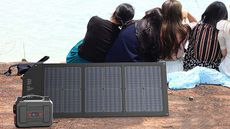 Group of people sitting beyond a portable generator connected to a solar panel