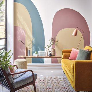 yellow sofa in front of wall with pink, yellow and blue colour blocking shape