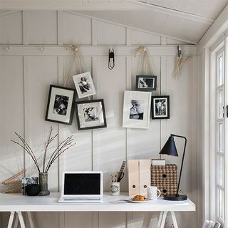 home office with wooden desk and photo frames on wall