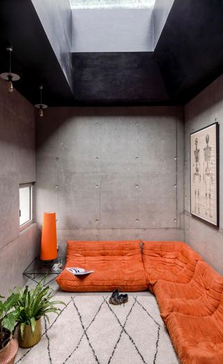Concrete living space with orange sofa