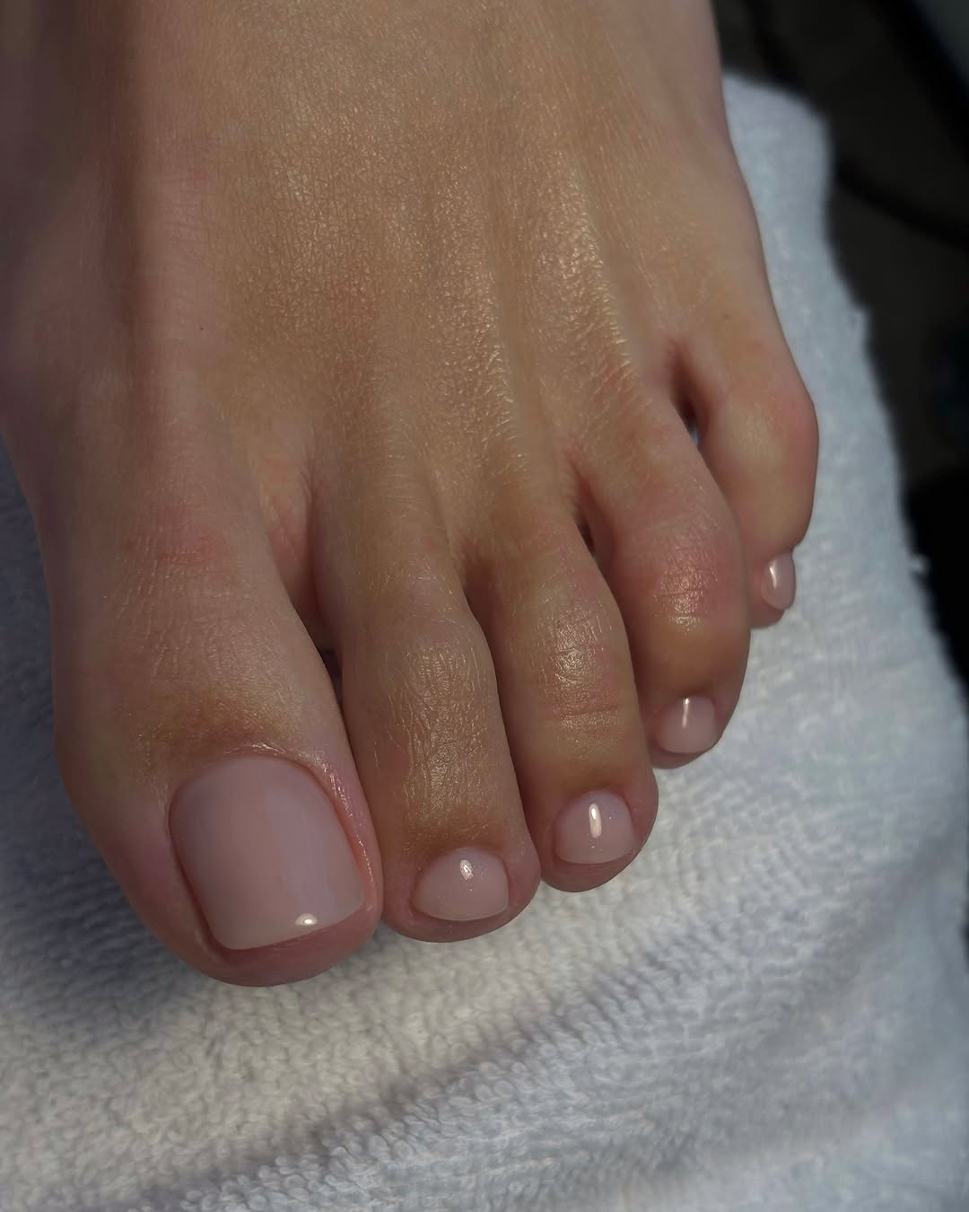 baby pink nail polish on a foot with a towel
