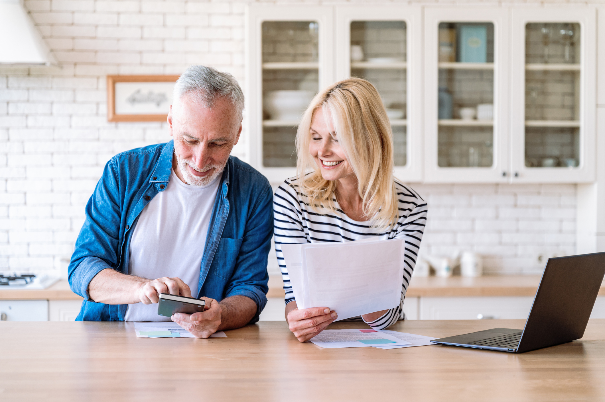 A couple managing their household budget together next to a laptop