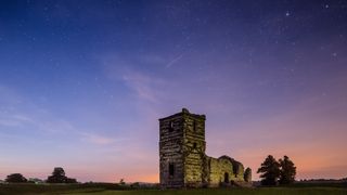 the ruins of a church stand tall in front of a starry sky.