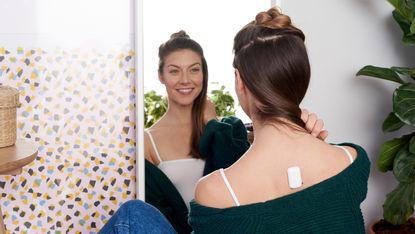 best posture corrector: Person sat in front of mirror wearing the Upright Go 2 posture corrector
