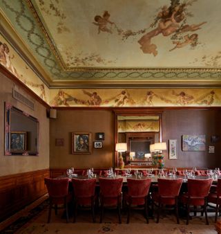 A plushily decorated tea room features frescoed ceilings and warm Art Deco-style lamps.