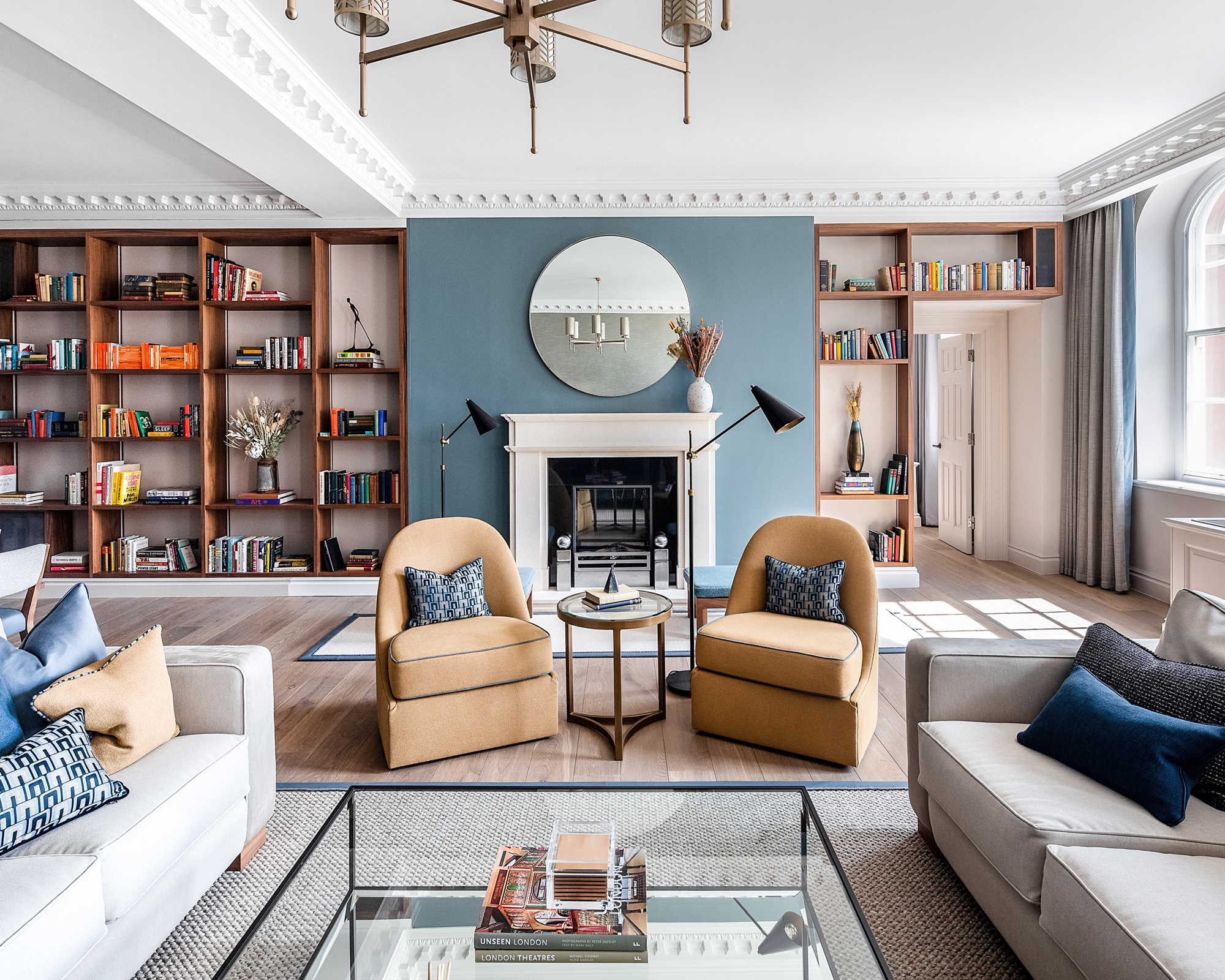 A living room with grey sofas, yellow armchairs and blue wall with fireplace