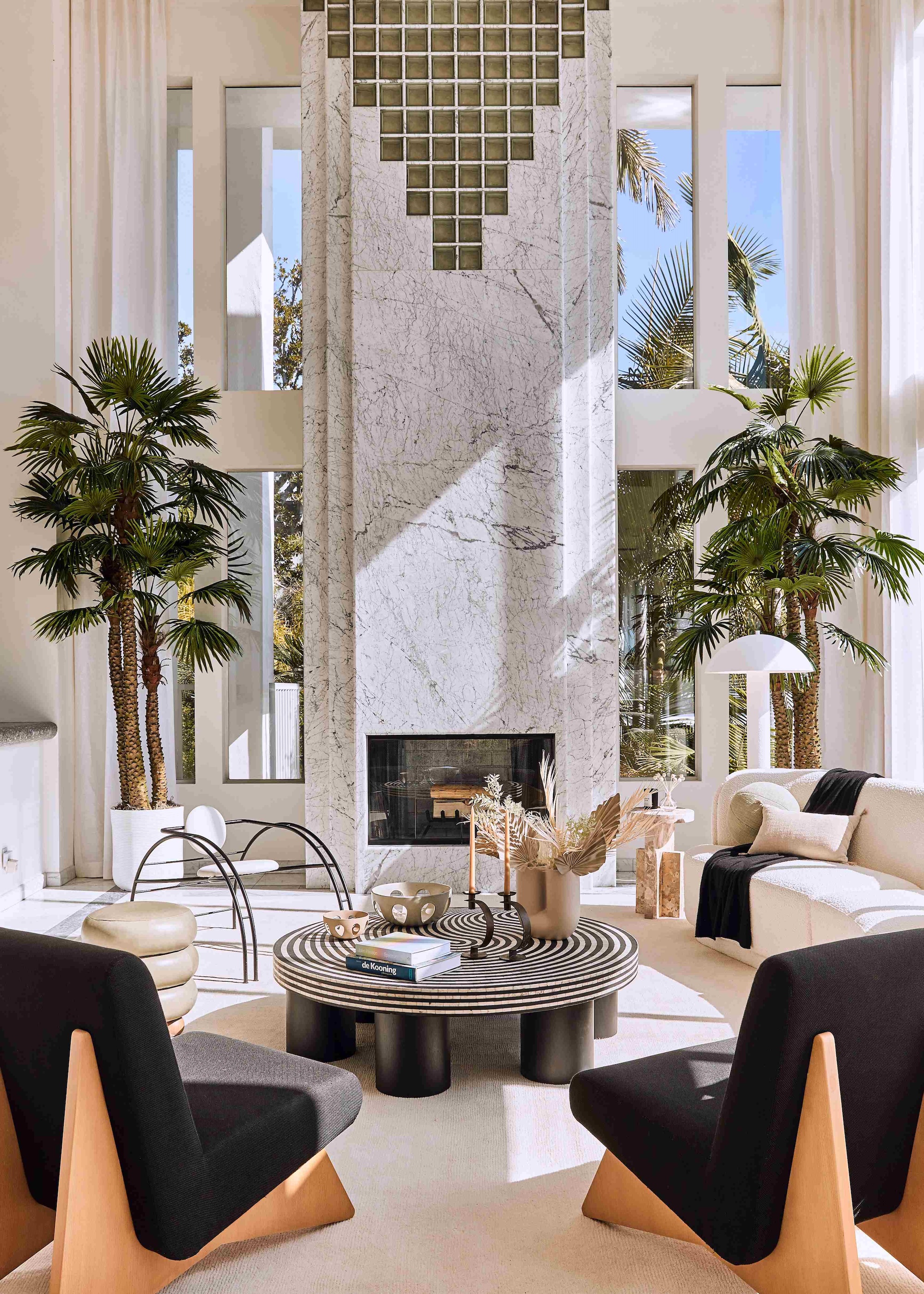 A sleek modern home with a huge statement fireplace and black and white furniture around it.