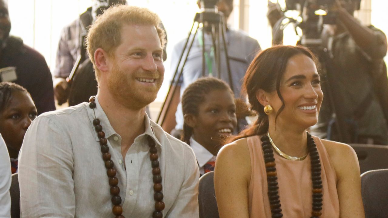 Prince Harry wears a shirt and Meghan Markle wears a pastel dress during a tour of Nigeria