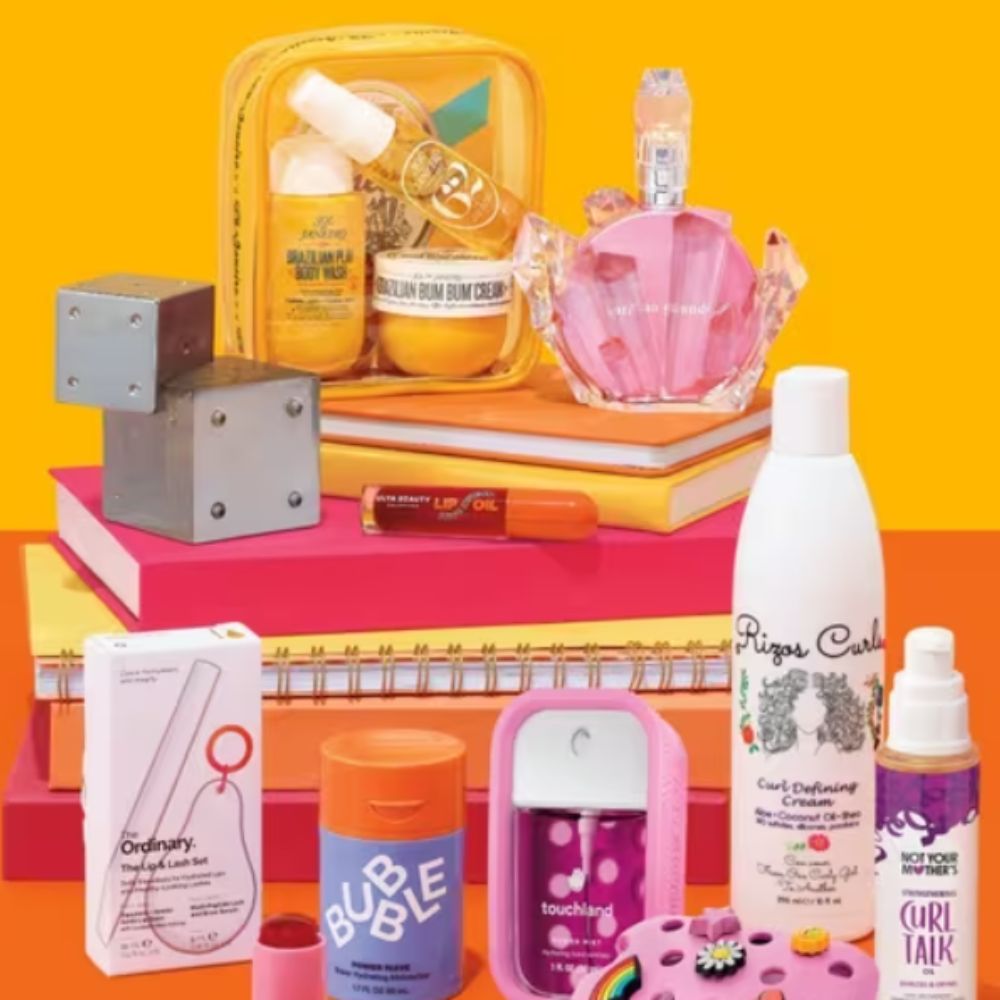 Beauty products from multiple brands on pile of notebooks and folders with orange and yellow background.