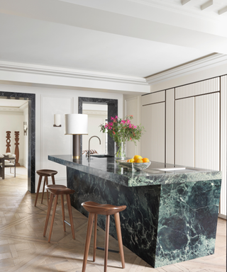 Modern marble kitchen island with in sink and surrounding wooden curved stools