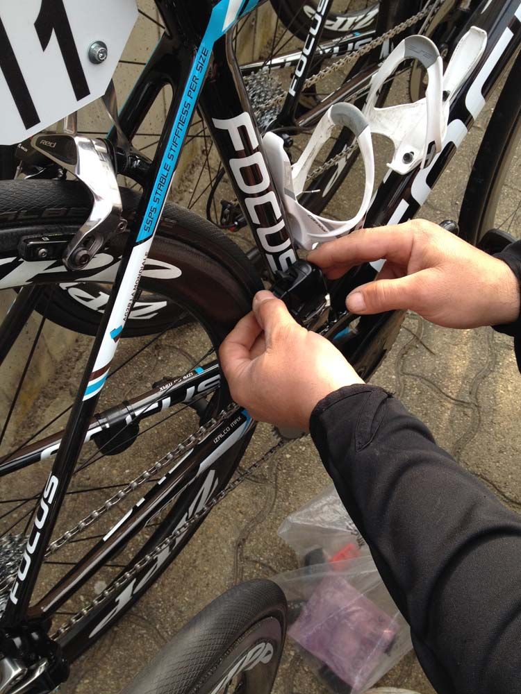 A mechanic places the battery into the front derailleur before the race start