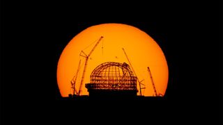 The construction site of the Extremely Large Telescope in Chile's Atacama Desert is silhouetted against the rising sun displaying sunspots.