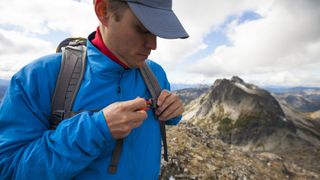 A man on a hike adjusts the chest strap of his backpack