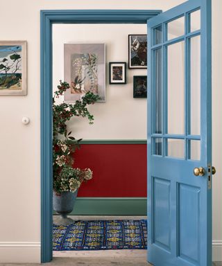 blue painted door and door frame with a hallway painted red by farrow and ball