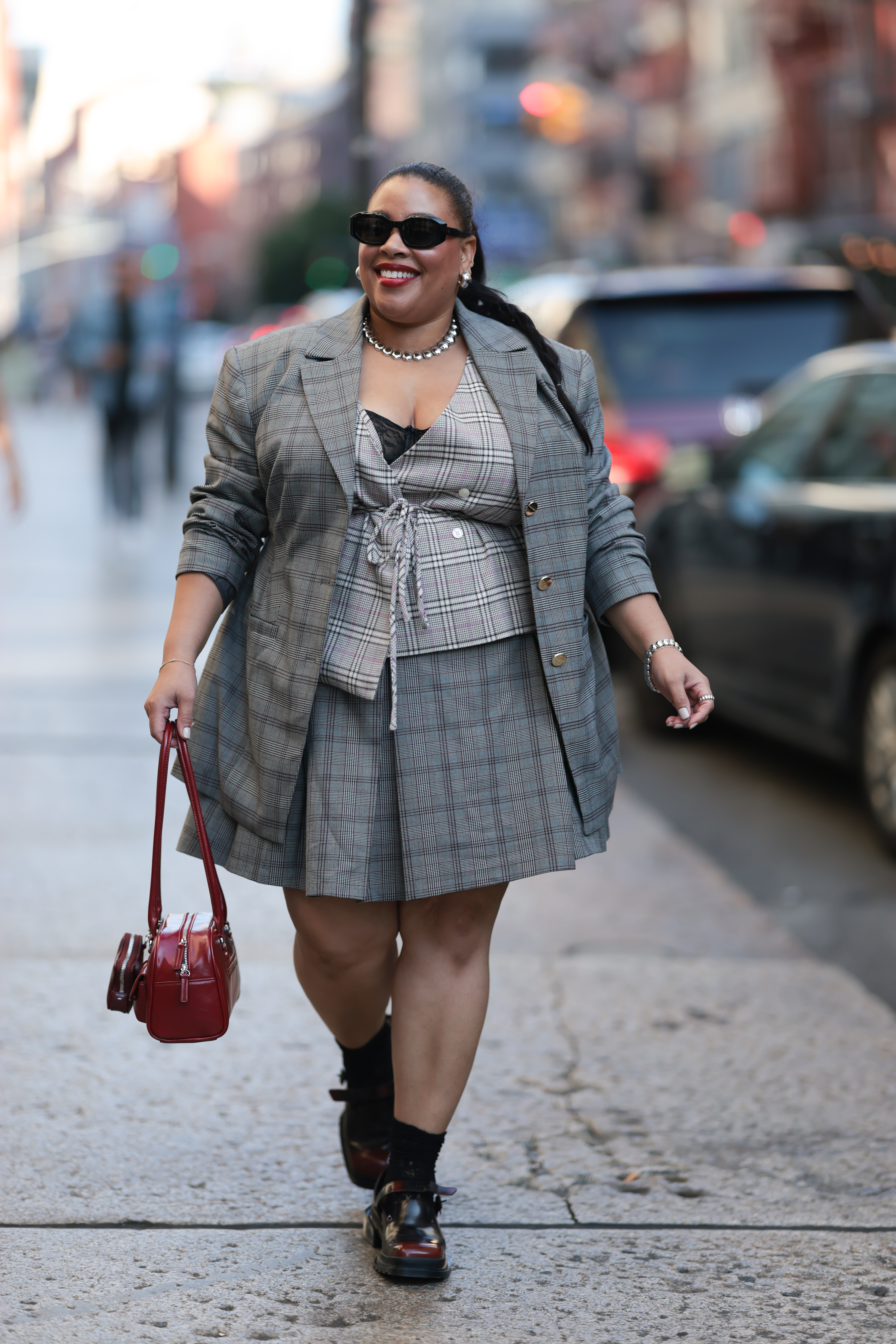 a woman wears a plaid skirt with loafers