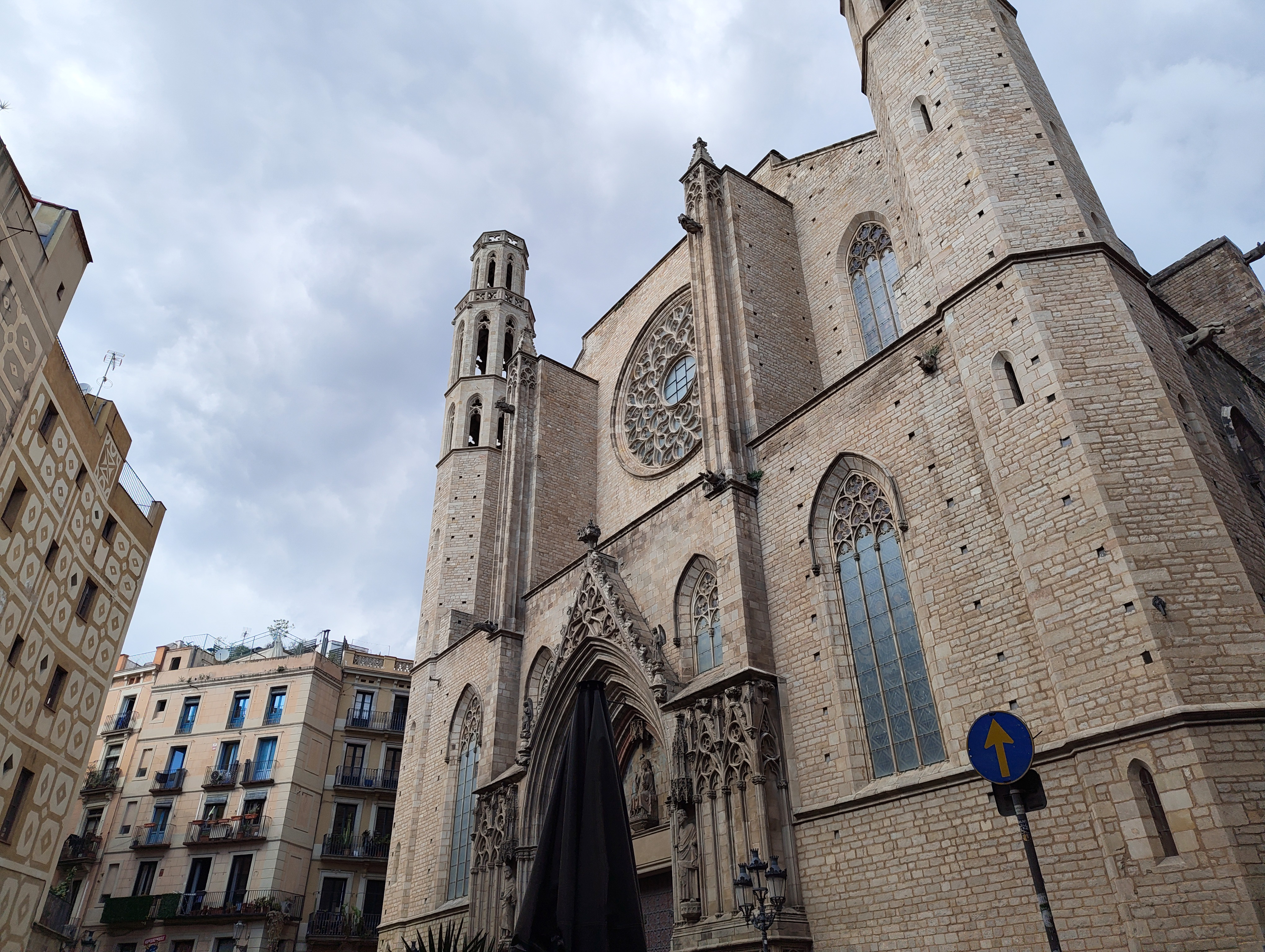 Gothic-style church with tall bell towers and a large rose window under cloudy skies in Barcelona, captured with the Nothing Phone (4a).