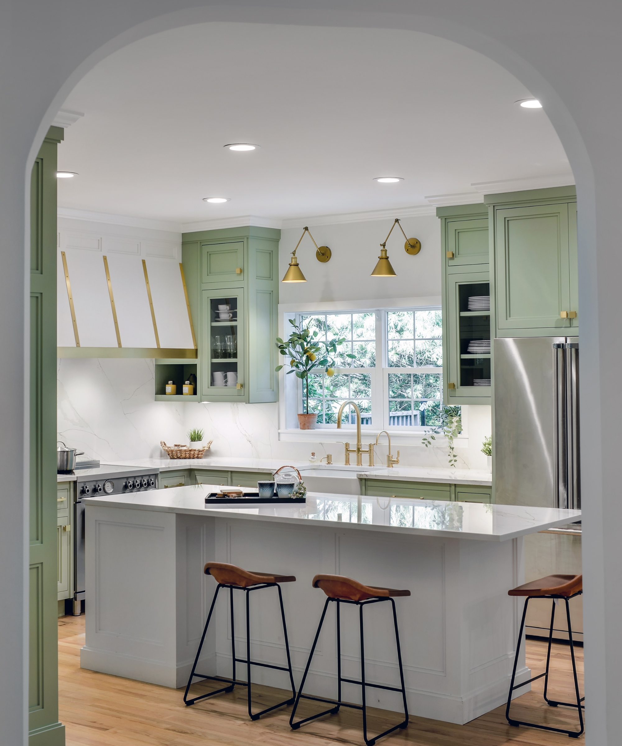 A large kitchen with light green cabinets and a white island
