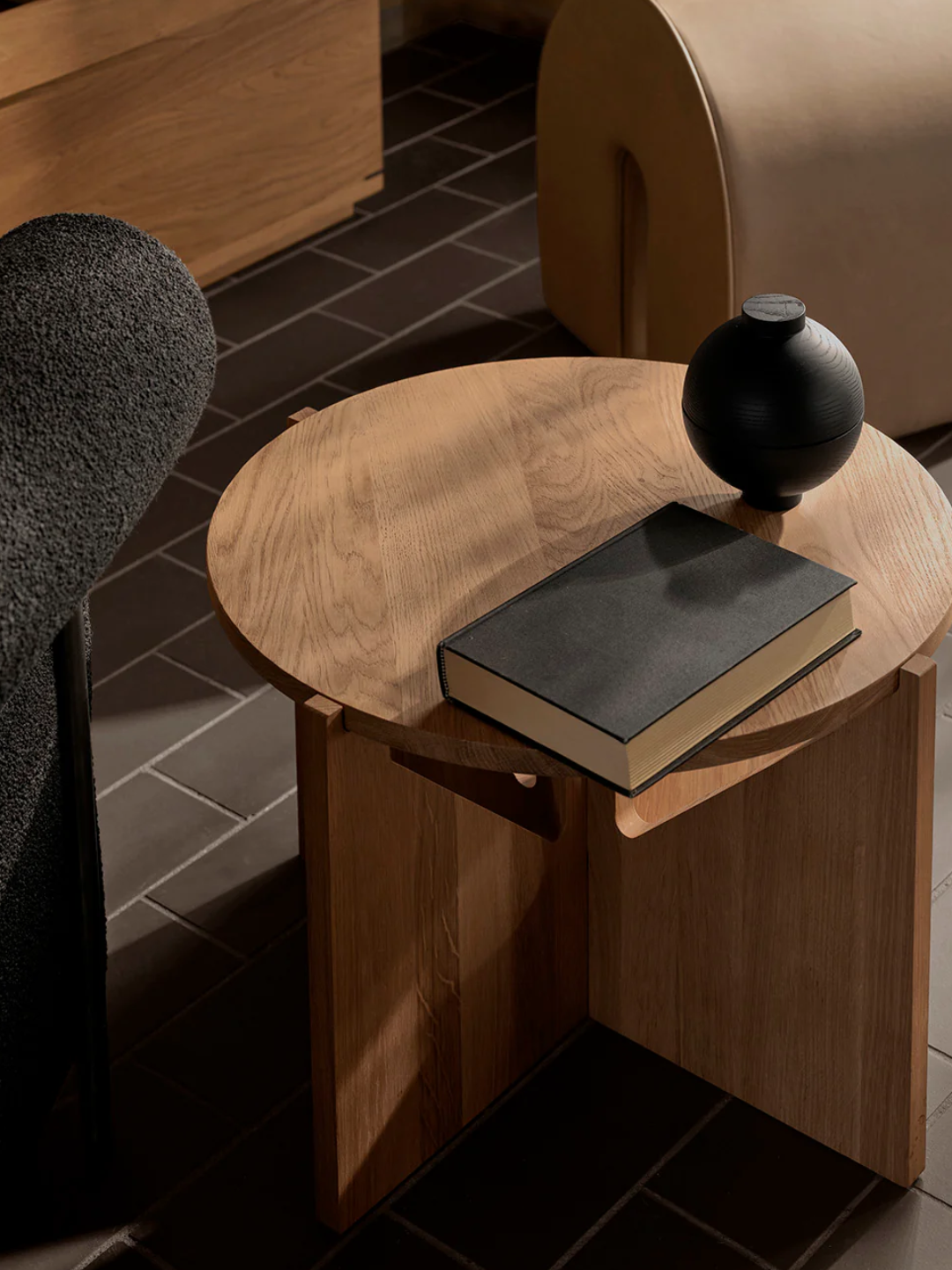 A round storage box on a side table by a book