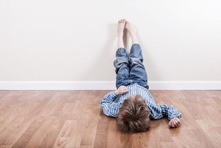A little boy in timeout puts his feet up