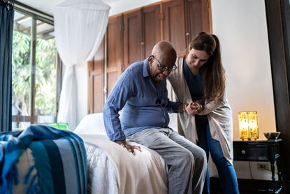 A nurse helps a nursing home resident get out of bed