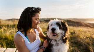 women smiling at her dog with dunes in the background