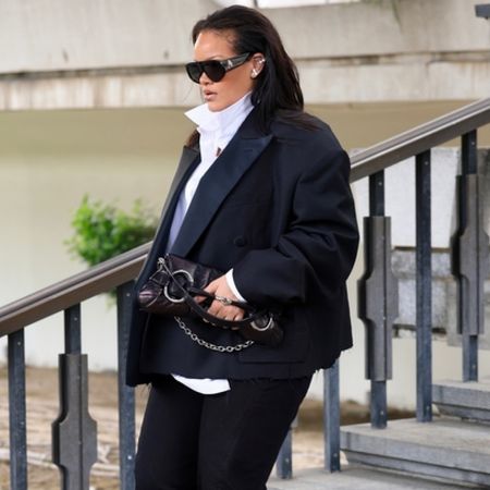 Rihanna walking down stars wearing an oversize blazer with a high neck blouse and a Gucci horsebit bag