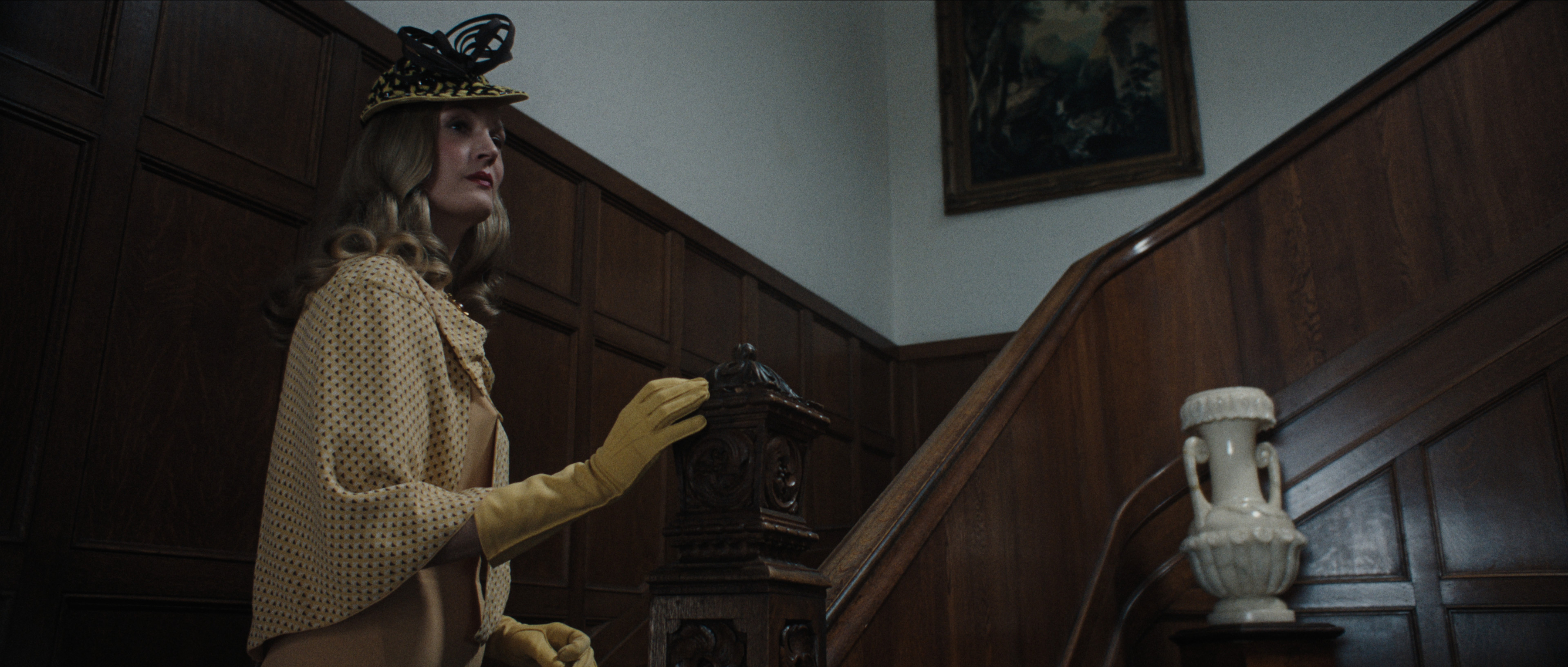Vicky Krieps as Isle Koch wearing a yellow outfit and climbing a staircase in monster the ed gein story