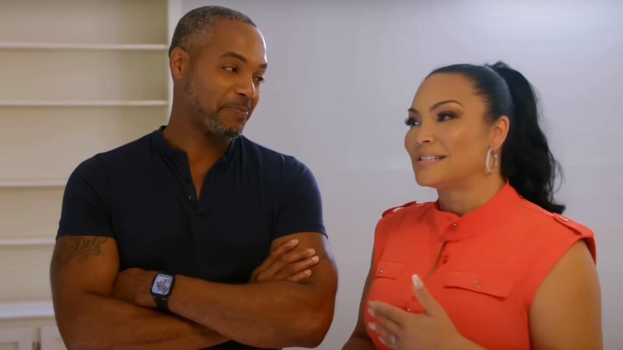 Mike Jackson smiles cross armed next to Egypt Sherrod as she speaks in Married to Real Estate.