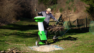 Best garden shredder 2024: image depicts man loading logs into shredder