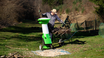 Best garden shredder 2022: image depicts man loading logs into shredder