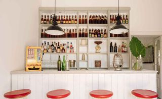 Bar with red bar stools and industrial hanging lights at the Hospedaria hotel in Portugal