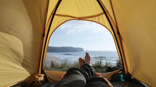 Person sitting in tent looking out over beach landscape