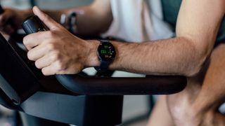 Man using exercise bike wearing Polar Ignite 3 Titanium watch