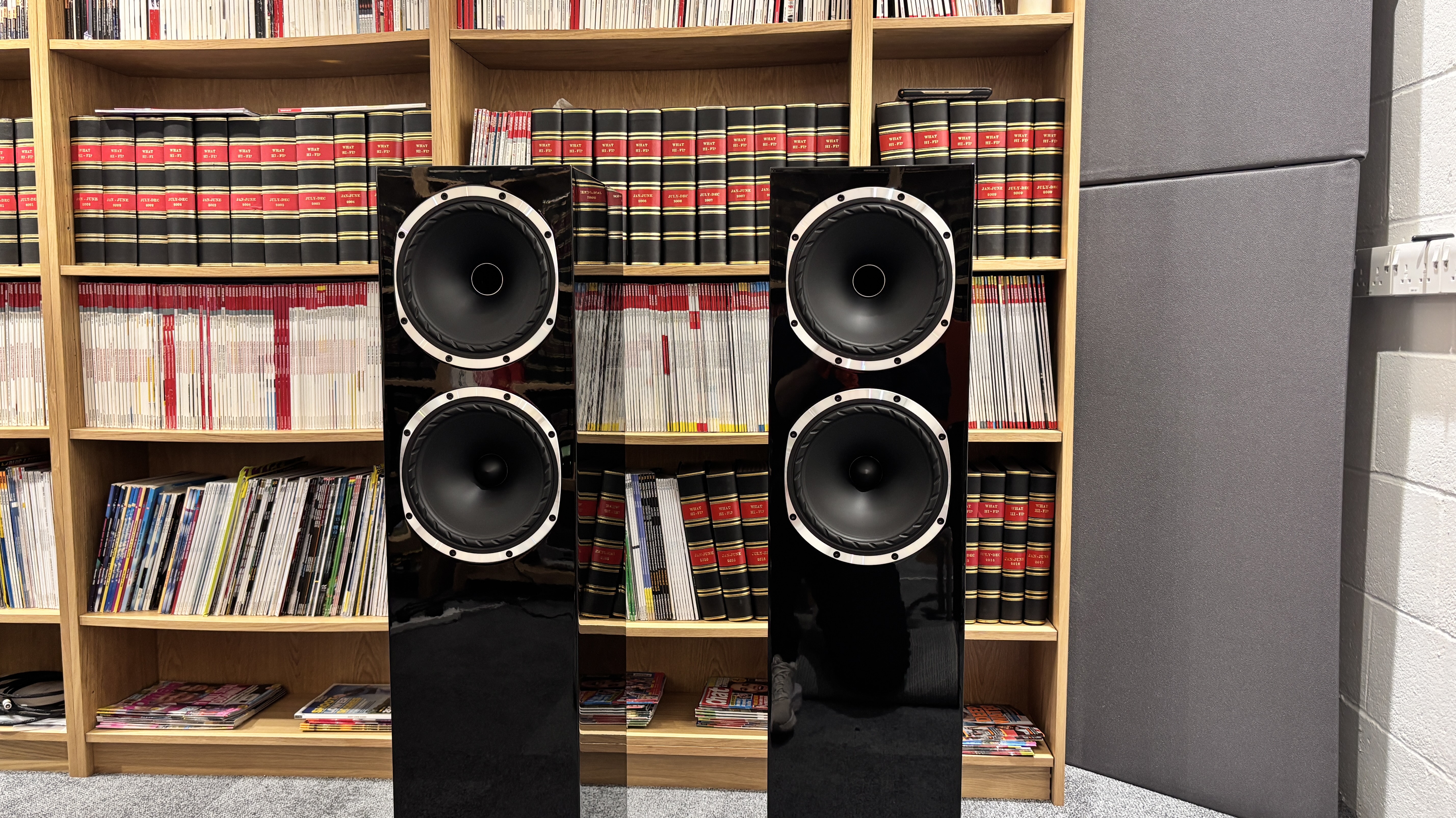 Fyne Audio F502S floorstanders in piano black in front of a bookshelf