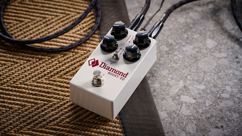 The Diamond Boost/EQ is a compact four-knob pedal in a white enclosure with black knobs and a toggle switch, and is photographed here in close-up against a patterned rug.