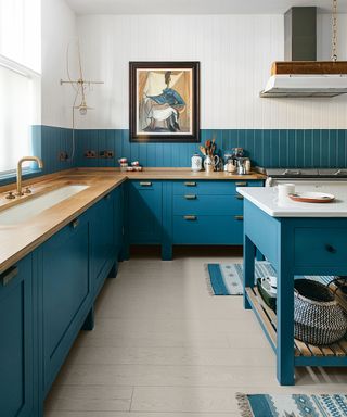 Blue and white country-style kitchen with blue painted cabinets, wood surfaces and wall panels