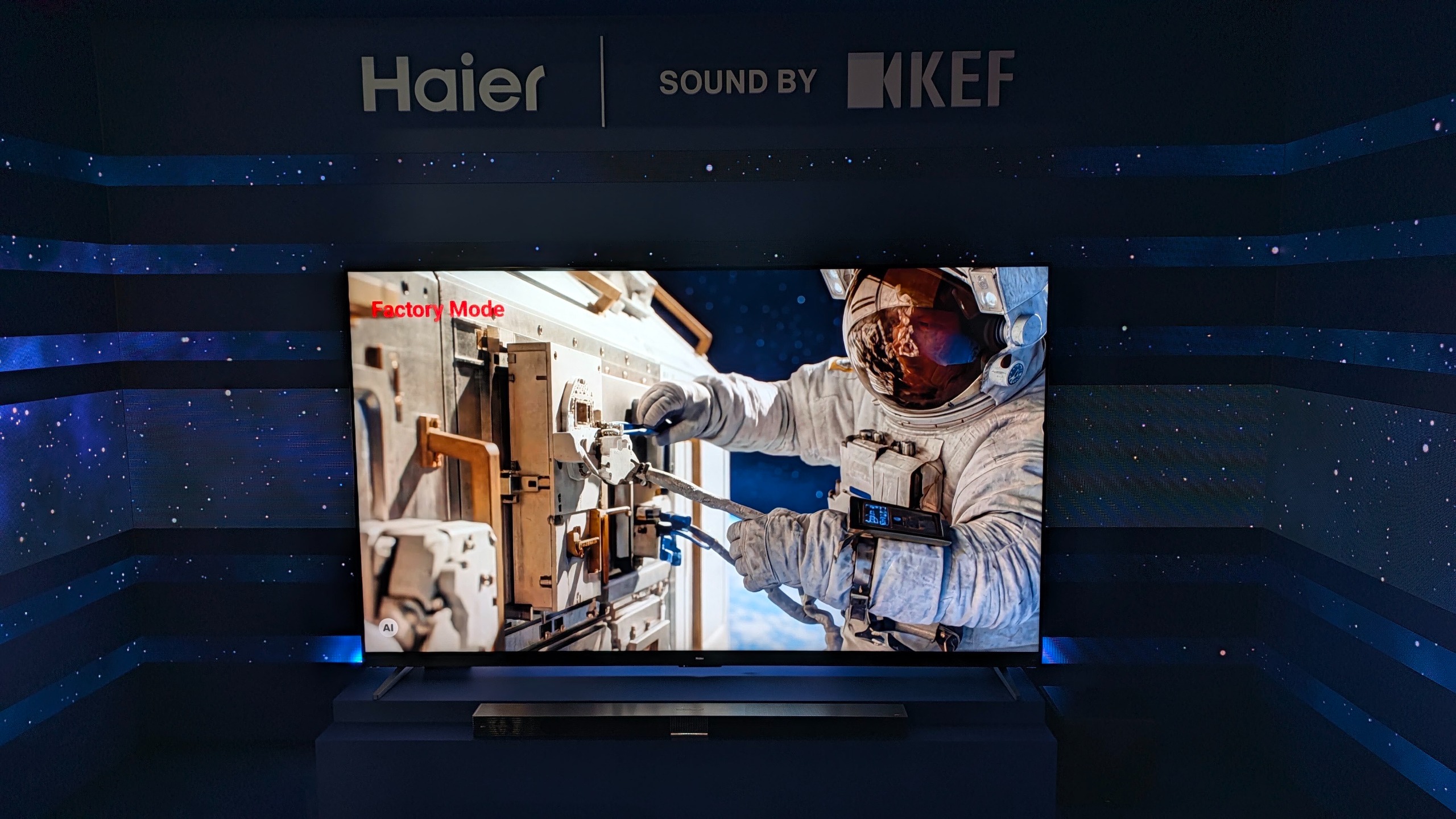 A Haier TV with an astronaut on screen in a dark room with writing above that reads "Haier | Sound by KEF"