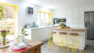 modern white kitchen with bar stools and splashes of yellow