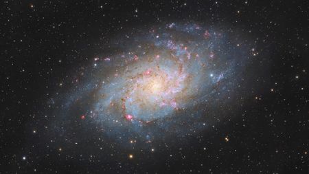 A large spiral galaxy with sweeping spiral arms and a glowing core shines against a sea of stars.