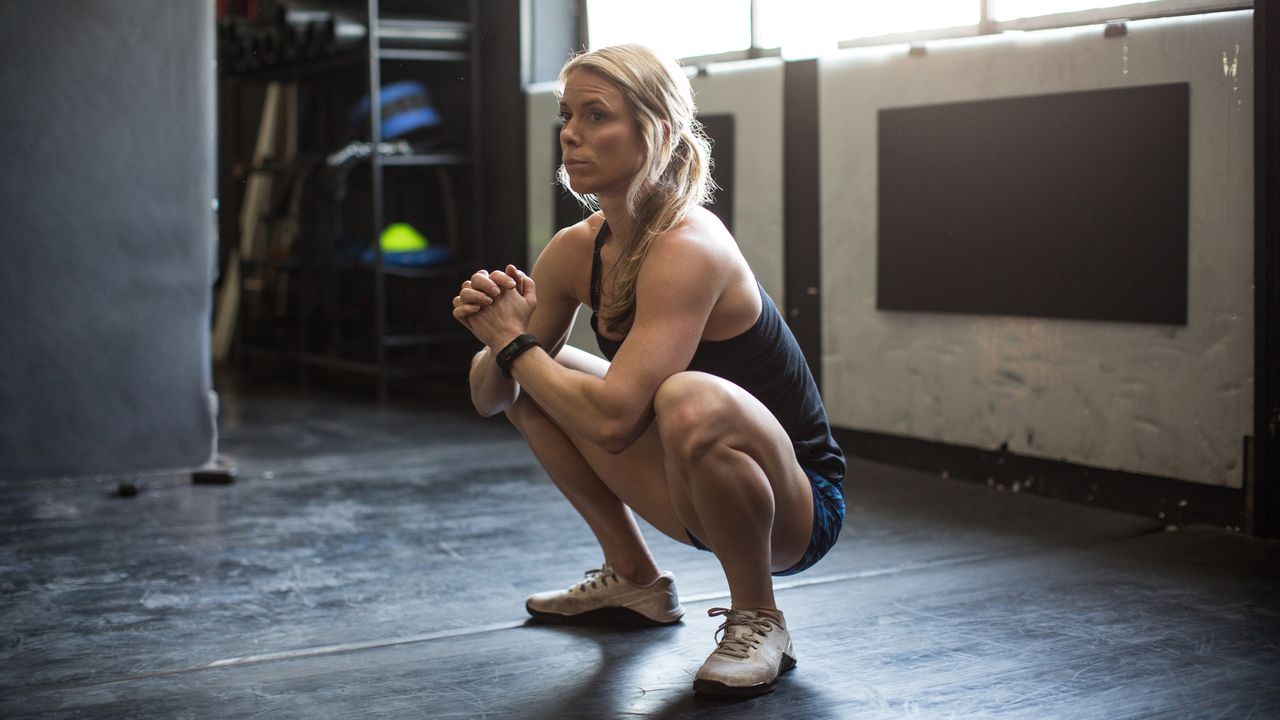 Woman in a gym sits in the deep squat position