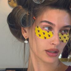 Hailey Bieber wearing eye patches and diamond drop earrings.
