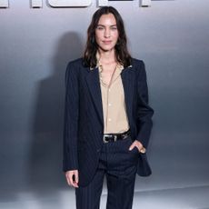 Alexa Chung wears a navy pinstripe suit with dark purple slim-line Hoff Trainers.