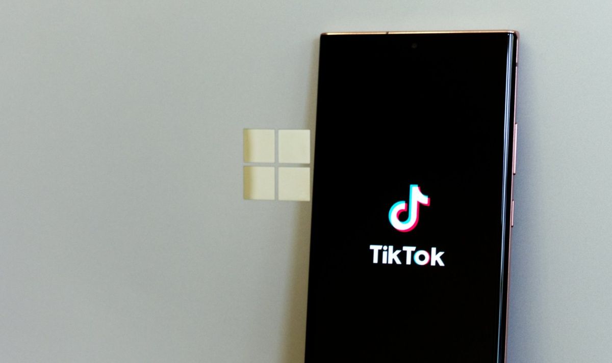 TikTok logo on a smart phone flanked by a Surface Book 